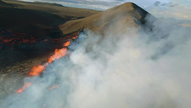 FPV aerial view over volcanic smoke, overlooking a bursting volcano basin in Iceland