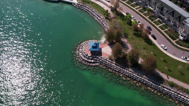 Aerial slow movement around Gazebo-Tall Oaks park surrounded by water with cars driving on road