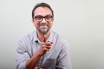 Middle aged smiling man of Indian origin shows pointing gesture