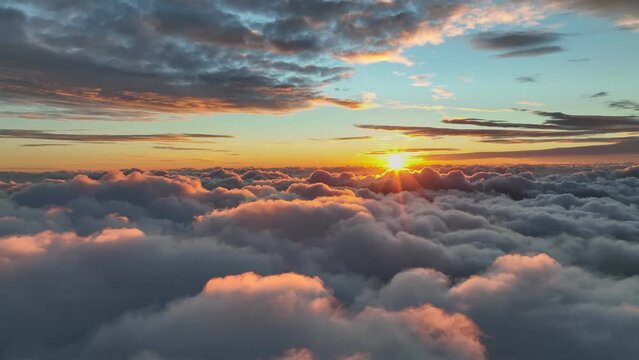 Flying above clouds at sunrise. Rising sun in the morning illuminates dense veil of clouds. Epic sunrise aerial shot