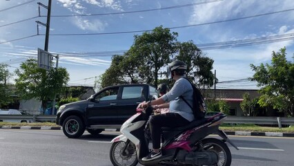 Motorcycles and cars passing by on Phuket road under blue sky. Fluid traffic on sunny day in Thailand. Vehicle ground transportation concept