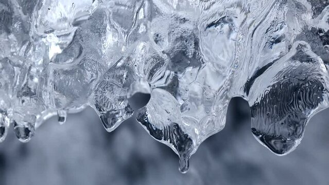 Ice melting. Drops of water slowly fall from the block of ice forming a river. Global climate change concept. Zoom out shot