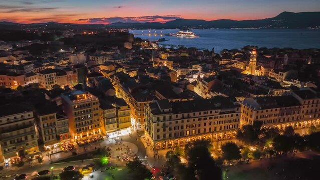 Evening aerial sunset view of Kerkyra, capital of Corfu island, Greece. Old town with illumination against background of red sunset sky in Kerkyra, Corfu island