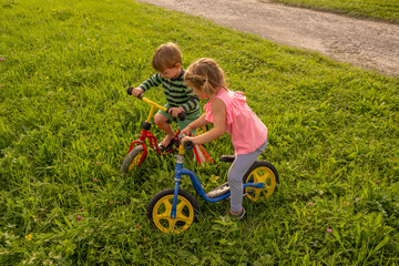 Girls and Boy having fun with their bicycles outdoors in the grass