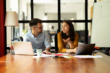 Fototapeta premium Colleagues in office. Businesswoman and businessman discussing work in office.