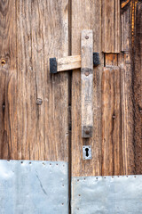 unvarnished antique wooden door with metal plate