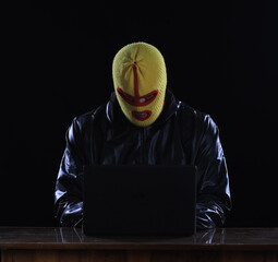 masked hacker with laptop at night