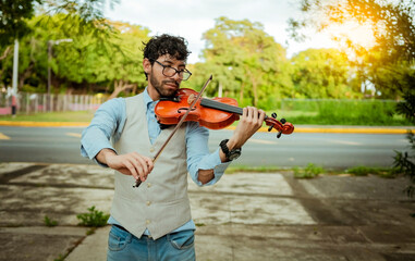Violinist artist playing a melody outdoors, Portrait of man playing violin outdoor. Close up of...