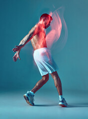 Strong man performing zumba dance. Young man dancing in white shorts with bare torso on blue background.