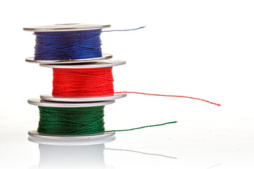 spools of thread in blue, red, green colors on a white background