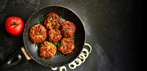 Meat cutlets. Cutlets in a pan on a black concrete table background. Delicious tasty food. Copy space. Top view.