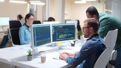 Young professionals writing on sophisticated programming code language and speaking with male boss at office. Team of IT programmers working on desktop computers in data center control room. Workflow - Powered by Adobe