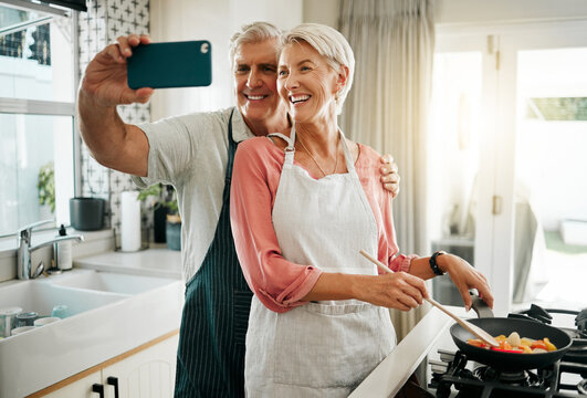 Old couple, phone selfie and cooking in kitchen, delicious meal and food in home. Love, smile and happy elderly retired romantic man and woman cook breakfast in the morning and take picture together.