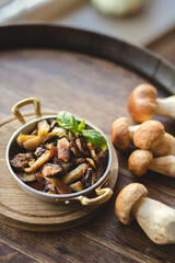 White mushrooms in a vintage frying pan on a wooden background.