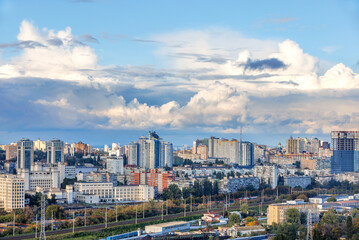 Cityscape, embossed white and gray clouds over dense urban areas on an autumn day.