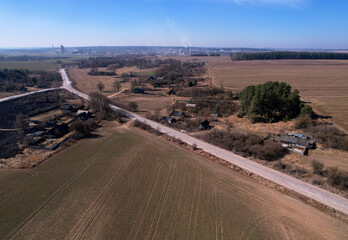 Road through the countryside, top view. A dirt road through an agricultural field, here from a drone. Field and road in middle, texture background. Rural landscape with arable land. Highway at field.