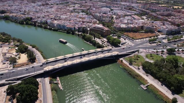 Aerial View of Seville, Spain, Traffic on Puente del Cachorro Bridge, Riverbank Buildings on Sunny Day, Drone Shot