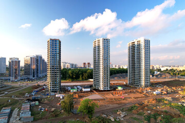 Obraz premium Facade of a new modern high-rise residential building. Construction of the skyscraper. Tall house renovation project. Construction site with minimalistic multi storied buildings. Glass facade.