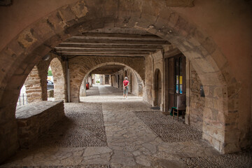 Touriste solitaire promenant sous les arcades du villde de sauveterre de Rouergue