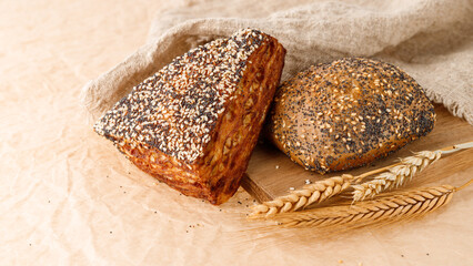 Fresh baked puff lye corner and bun with poppy and sesame seeds closeup on wooden board.
