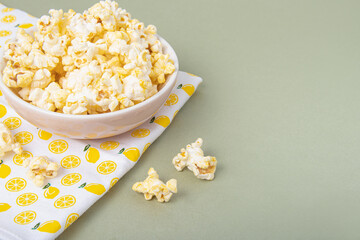 Popcorn in small plate on green background. Space for text