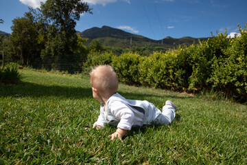 Happy little boy crawling in the grass