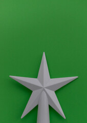 Vertical Christmas background. On a green background, a white star at the bottom of the photo. New Year layout. Minimalism. Card. Place for text. Selective focus.