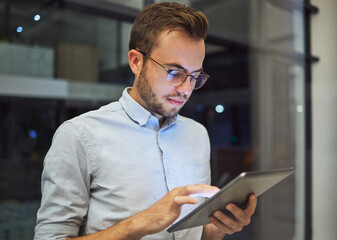 Man in the office, at night with digital tablet and working overtime. Professional business man in online marketing company, planning corporate strategy and testing new web feature to increase growth