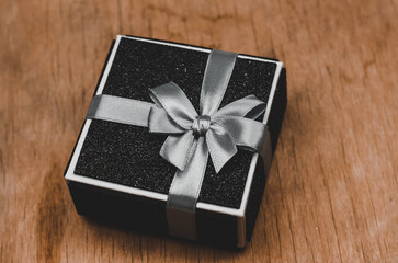 Black gift box on a wooden background.