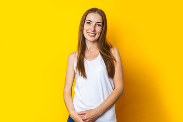 Beautiful smiling young woman with long hair on a yellow background