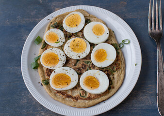 Oatmeal pancake with boiled and sliced eggs isolated on wooden background