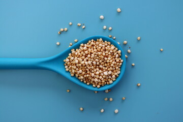 Quinoa popcorn in a blue spoon on a blue background. 