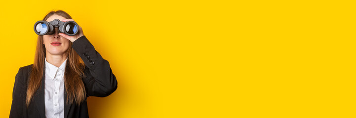 young business woman looking through binoculars on a yellow background. Banner