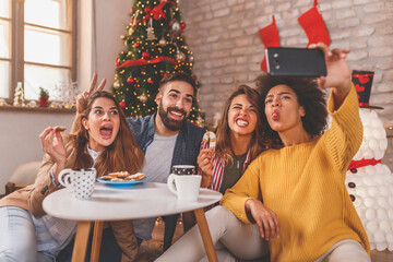 Friends having fun taking selfies while celebrating Christmas at home