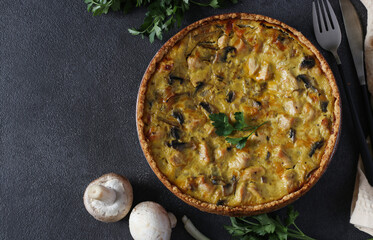 Traditional french quiche pie with turkey, mushrooms and cheese in plate on dark gray background, Top view
