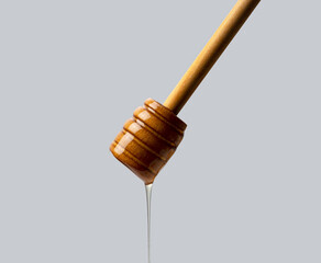 Honey and wooden honey dipper on gray background.