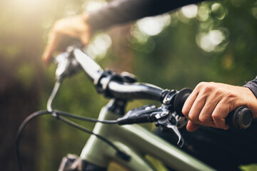 Forest, mountain biking and trees, hands on handlebar closeup with bokeh. Fitness, health and a man on a bike on outdoor adventure trail. Nature, freedom and exercise, cycling in park on a summer day
