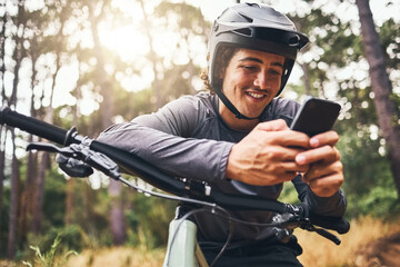 Fitness, bike and phone with man texting and cycling in a forest, happy and relax in nature with...