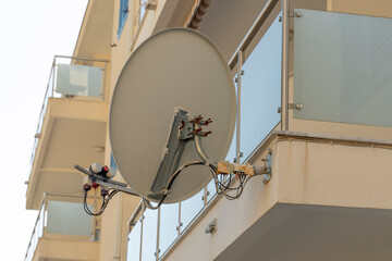 TV dish on the balcony Denmark. A TV dish connected by wires transmits information via satellite....