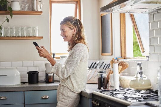 Mature woman reading phone news, social media notification and mobile apps in Australia kitchen home. Happy lady typing smartphone, online social network and 5g web technology connection in apartment