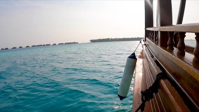 Low side view of Wooden boat in ocean sailing towards island