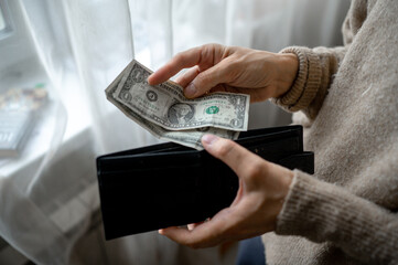 A woman's hand close-up pulling dollar bills out of her purse