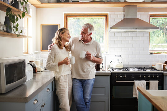 Senior, couple and drinking coffee with a love, marriage and happiness morning mindset at home. Happy smile and hug of a elderly woman and man with tea in a house kitchen together with quality time