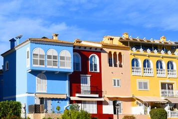 Yachts and motor boats in marina Port Saplaya, Valencia, Alboraya, Spain. Luxury yacht and fishing motorboat in yacht club on background of the colourful houses at Mediterranean Sea. Sailboat port.