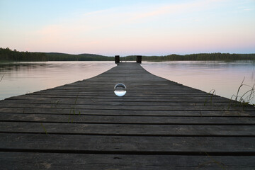 Glass ball on a wooden walkway on a Swedish lake at the blue hour. Nature Scandinavia