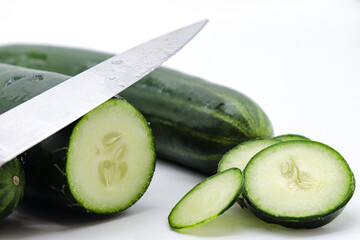 cut cucumber with knife on white background