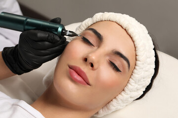 Young woman undergoing procedure of permanent eyeliner makeup on grey background, closeup - obrazy, fototapety, plakaty