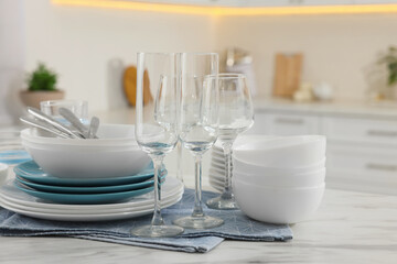 Fototapeta na wymiar Different clean dishware, cutlery and glasses on white table in kitchen