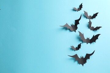 Flat lay composition paper bats on light blue background, space for text. Halloween decor