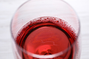Glass of delicious rose wine on white table, closeup